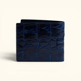The Monarch Crocodile Bifold Wallet in Deep Midnight Blue crafted from genuine crocodile leather, featuring a clean rear exterior with a natural scale pattern and slim bifold profile, shown in a back view on a soft ivory background.
