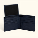 The Monarch Crocodile Bifold Wallet in Deep Midnight Blue featuring a premium leather interior with six card slots, dual slip pockets, a full-length bill compartment, and a flip-up ID window, displayed open on a soft ivory background.