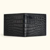 Full open exterior view of The Ashford black Siamese crocodile bifold wallet, showcasing the continuous full-belly cut and distinctive natural scale pattern.