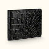 Angled view of The Ashford luxury black Siamese crocodile bifold wallet, highlighting the full-belly exterior, natural scale pattern, and slim handcrafted profile.