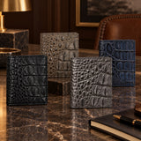 The Compact Crocodile Wallet collection in Graphite Gray, Taupe Green, Deep Navy and Classic Black displayed together in a luxury setting