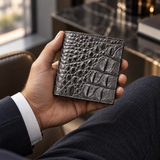 Compact Crocodile Wallet held in hand with tailored navy suit, showing its refined scale and luxury finish