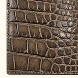 Close-up of The Compact Crocodile Wallet in taupe green showing natural crocodile scale texture and detailed stitching