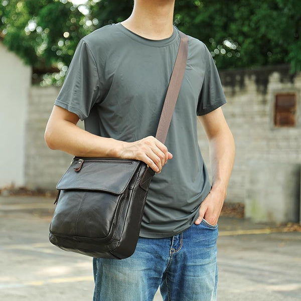 Lifestyle photo of The Dustwalker full-grain cow leather crossbody iPad bag worn outdoors with casual outfit, showing adjustable strap and front flap design.