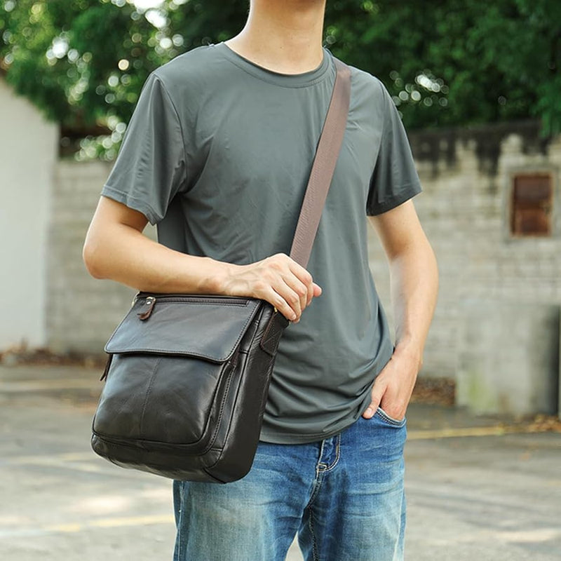 Lifestyle photo of The Dustwalker full-grain cow leather crossbody iPad bag worn outdoors with casual outfit, showing adjustable strap and front flap design.