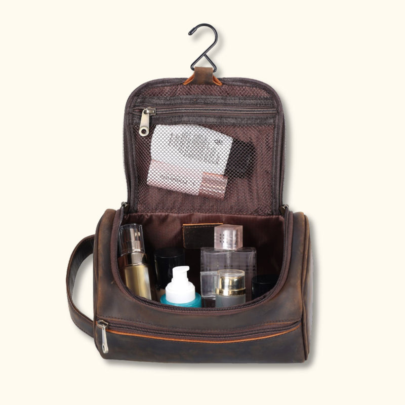 The High Plains Leather Toiletry Bag opened to reveal its spacious interior, featuring various toiletries and cosmetics neatly stored, with a hanging hook for convenience and mesh zippered pockets for organization.