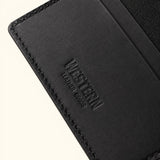 Close-up of The Rancher's Legacy black handcrafted leather cardholder showing the embossed Western Leather Goods logo, fine leather grain, and precise stitching.