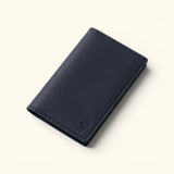 Angled view of The Rancher's Legacy black slim cowboy wallet featuring smooth leather, an embossed cowboy logo, and reinforced edge stitching.