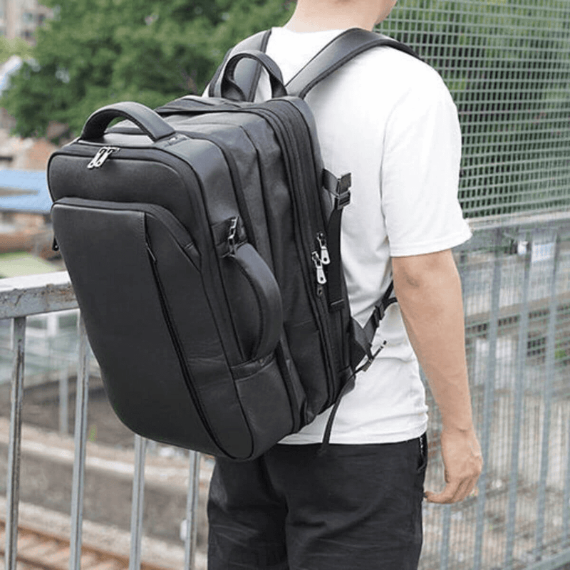 The Stetson Peak - Expandable Men's Leather Backpack in dark brown, worn by a person in a white t-shirt, showcasing the backpack's capacity and comfort while being worn.