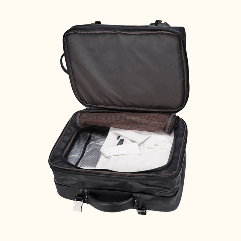 The Stetson Peak - Expandable Men's Leather Backpack in dark brown, open to reveal a spacious compartment with neatly packed clothing, demonstrating its use as travel luggage.