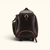 The Lawful Leather Duffle with Wheels handle side view featuring premium full grain leather, a telescoping handle compartment, reinforced side panel, brass D ring, and durable travel construction.