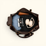 The Lawful Leather Duffle with Wheels packed with travel essentials, showcasing the spacious main compartment, interior organization, wide opening, and generous storage capacity for business or weekend travel.