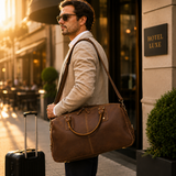 Business traveler carrying The Wolf leather travel duffel outside a luxury hotel, styled with an adjustable shoulder strap and carry-on luggage.