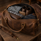 Packed view of The Wolf large-capacity leather travel duffel holding clothing, boots, a toiletry bag, and travel essentials.