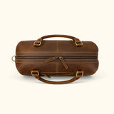 Top view of The Wolf leather travel duffel featuring a wide dual-zipper opening, reinforced carry handles, contrast stitching, and antique brass hardware.