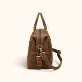 Side view of The Wolf men’s leather carry-on duffel showing its top zipper, structured side panel, brass hardware, and adjustable shoulder strap.
