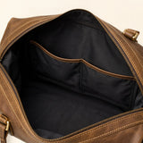 Interior close-up of The Wolf organized leather travel duffel showing black fabric lining, divided storage pockets, leather trim, and a wide zip opening.