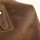 Close-up of The Wolf premium crazy horse leather duffel showing its rich brown grain, natural distressed texture, reinforced stitching, and metal rivet detail.