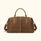 Front view of The Wolf vintage leather weekender duffel with a zippered exterior pocket, detachable shoulder strap, and reinforced carry handles.